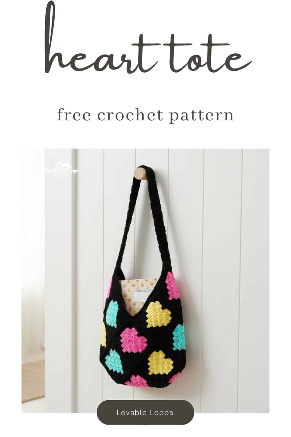 Pinterest pin for a free crochet heart tote pattern featuring a black shoulder bag with pink, yellow, and aqua heart motifs and a notebook tucked inside.