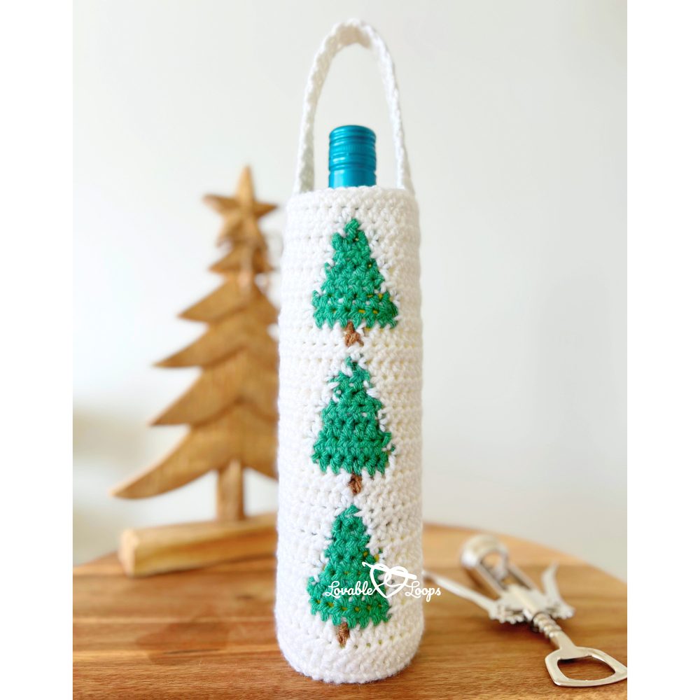 A Christmas crochet wine bottle holder in festive colors, designed for the winter season with pine tree inspiration, perfect as a handmade gift or gift bag for wine bottles.