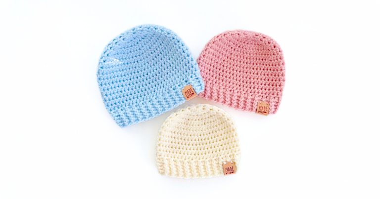 Three crochet baby hats made with the same simple pattern in pastel blue, pink, and cream yarn. Each beanie features a ribbed brim and smooth crown, laid flat. These hats are made using beginner-friendly stitches and follow the free easy crochet baby hat pattern.