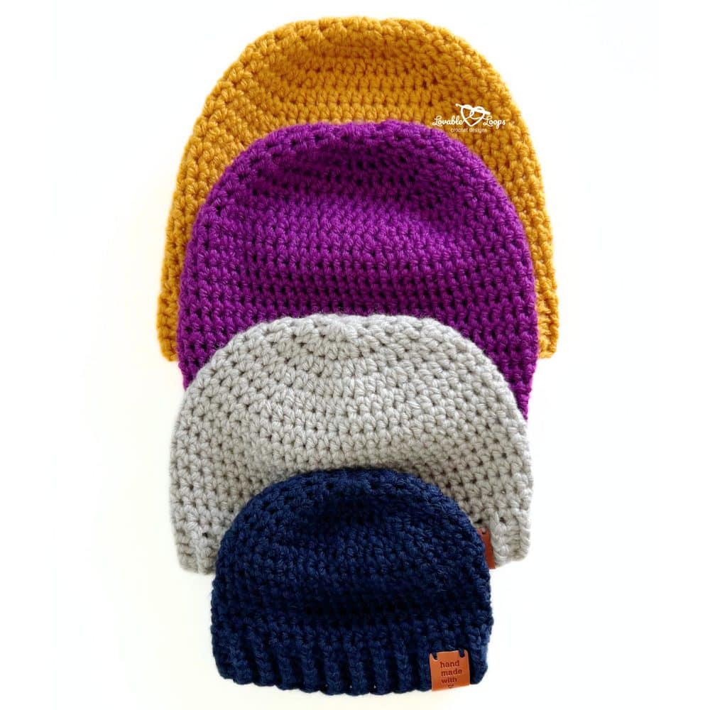 Set of four beanies stacked by size from baby to adult, in mustard, plum, gray, and navy. Easy crochet beanie pattern for all sizes.