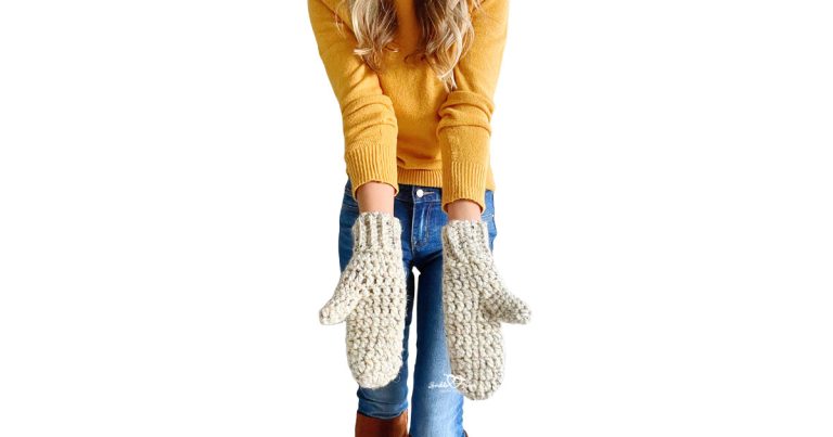 Woman wearing handmade crochet mittens made with chunky yarn in oatmeal color. Arms extended forward. Great visual for a beginner-friendly crochet mittens pattern.