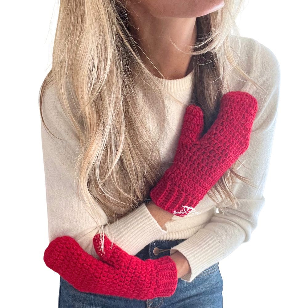 Side view of woman modeling red handmade crochet mittens. The mittens feature simple stitches and a stretchy ribbed cuff. Great photo for showcasing a free and easy crochet mitten pattern.
