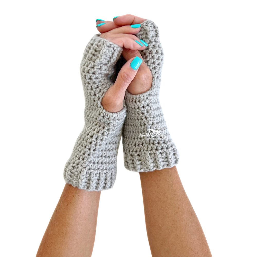 Front view of light gray fingerless gloves made using beginner crochet stitches and ribbed cuffs. Hands are gently clasped, showing off the comfort and handmade texture of this easy “crochet fingerless gloves pattern.” Ideal for showcasing warm winter accessories.