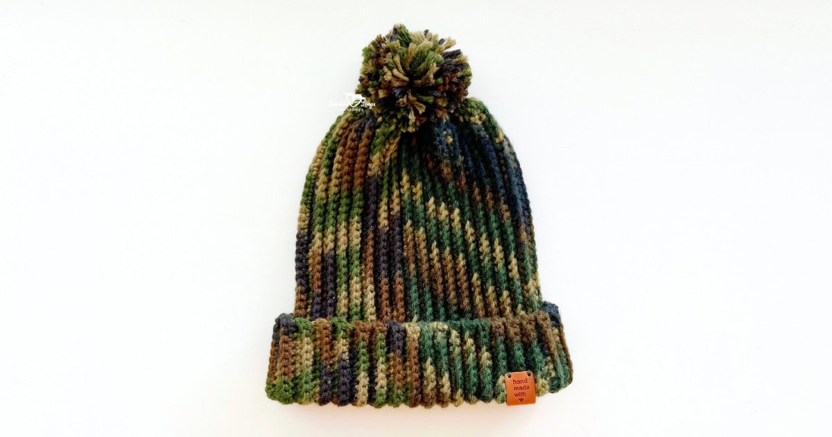 Camouflage ribbed beanie with a pom pom, laid flat on a white background. This free crochet hat pattern for men is beginner-friendly, made with single crochet stitches worked flat. Great for winter or handmade gifts.