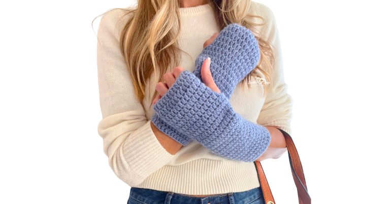 Woman wearing soft blue crochet fingerless gloves made with simple double crochet stitches. The gloves have an open thumb hole and reach mid-forearm. Stylish and cozy winter accessory handmade from worsted weight yarn—perfect for beginners following a free fingerless gloves crochet pattern.
