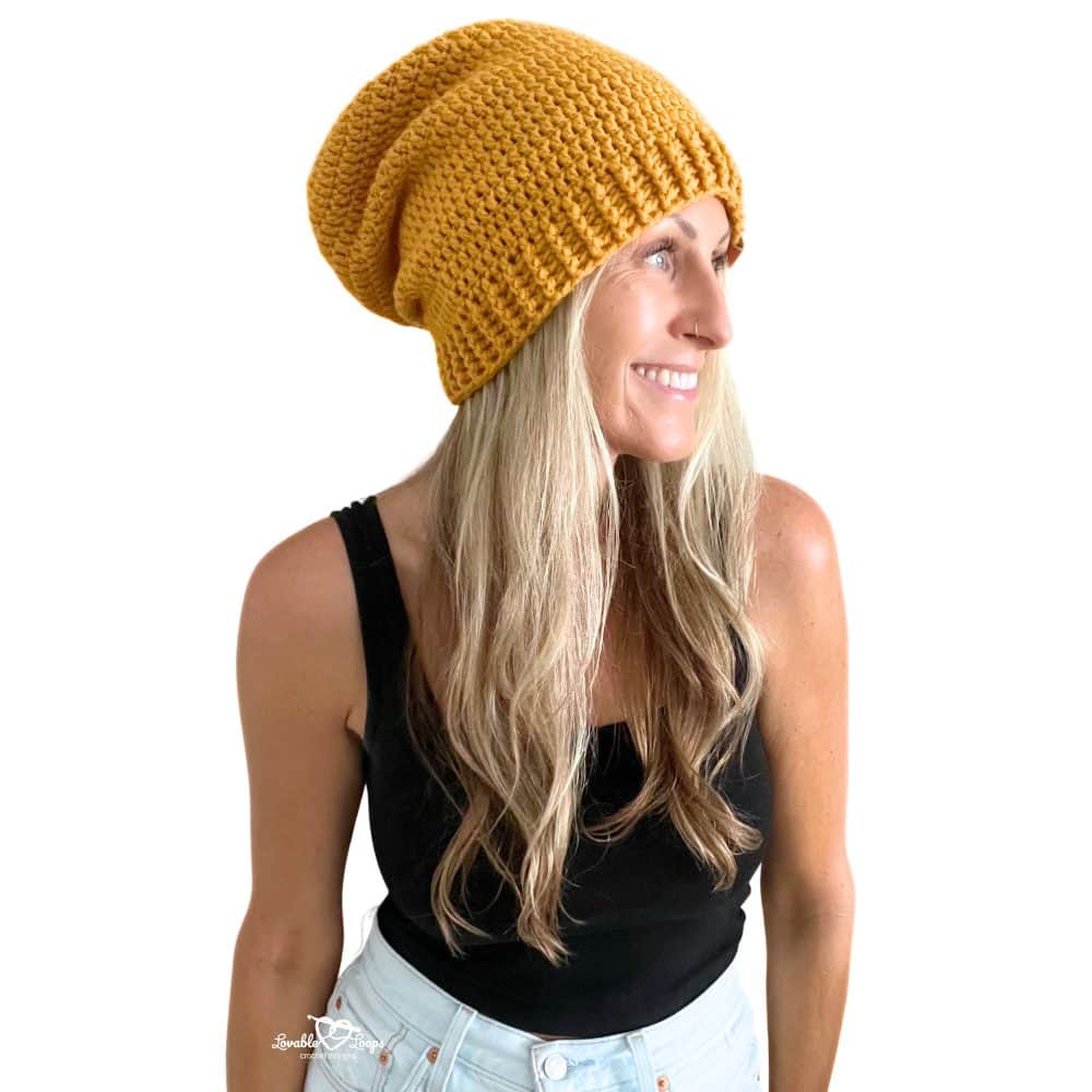Woman wearing a mustard yellow crochet slouchy beanie with a ribbed brim, part of an easy beginner-friendly crochet pattern.