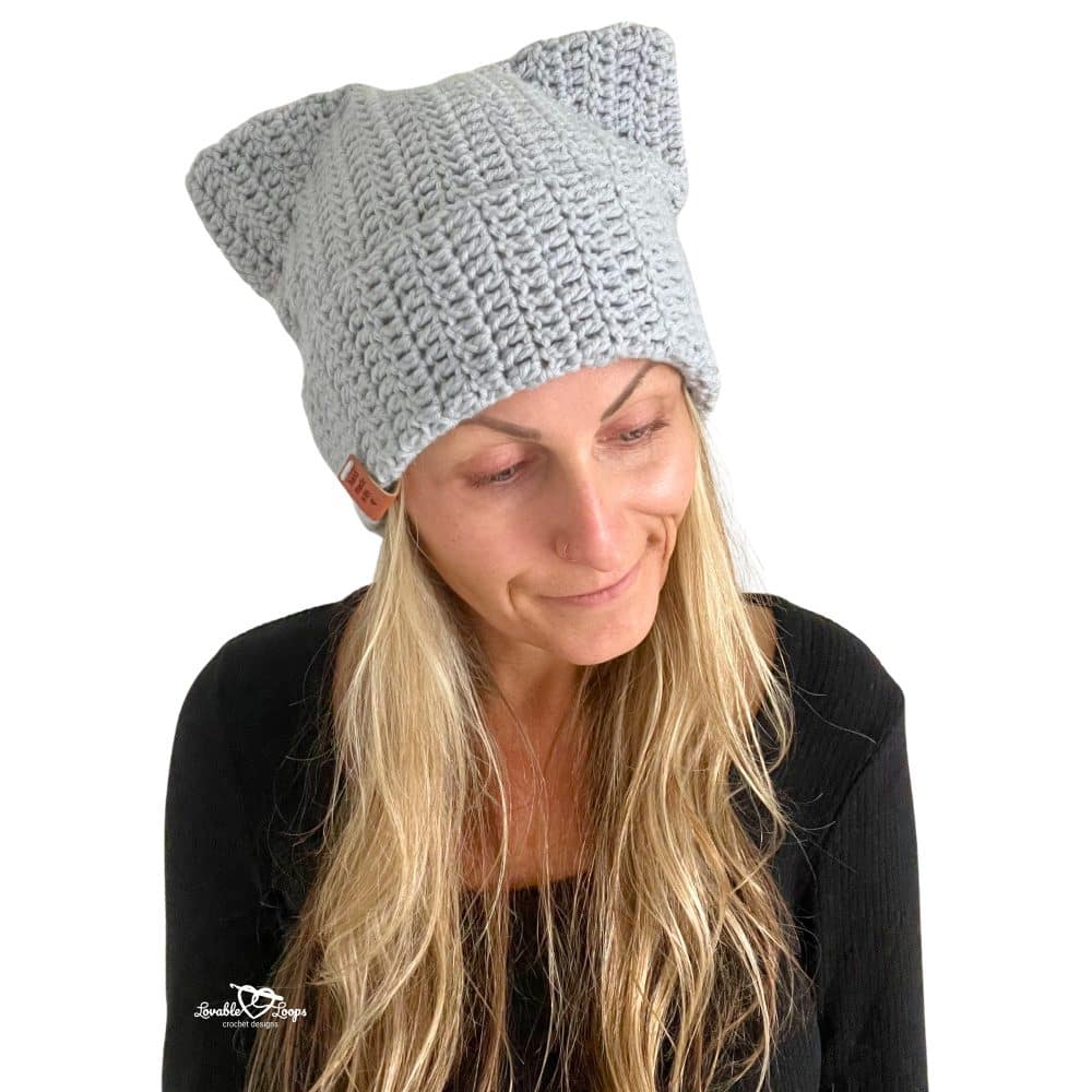 Woman modeling a gray crochet cat beanie with folded brim and pointed cat ears. Fun and easy crochet cat hat pattern for teens and adults.
