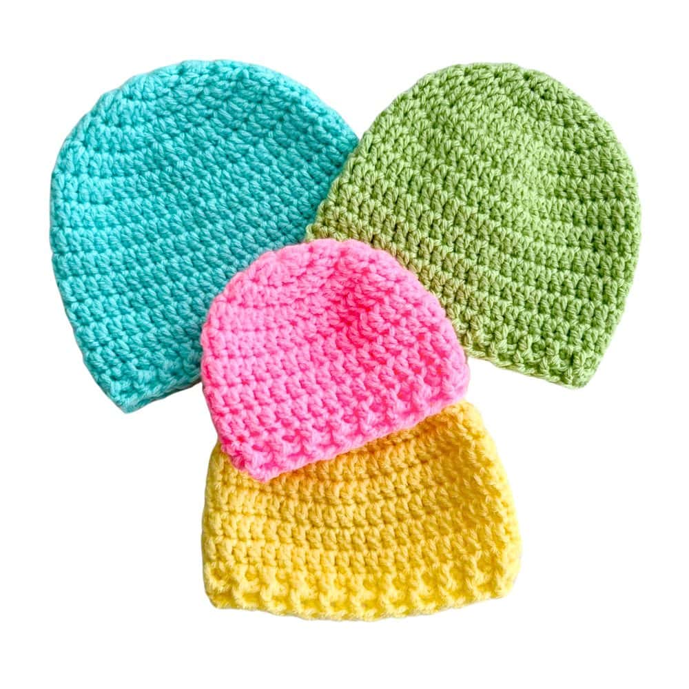 Four crochet newborn hats in turquoise, green, pink, and yellow displayed together. Beginner-friendly free crochet newborn hat pattern worked with simple stitches.