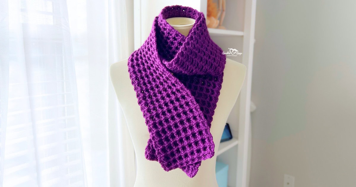 Handmade deep purple waffle stitch crochet scarf displayed on a mannequin, folded neatly around the neck to show texture and stitch detail.