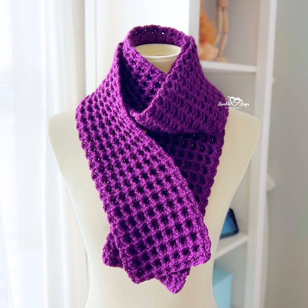 Close-up of a deep purple waffle stitch crochet scarf draped on a mannequin, highlighting the textured stitches and cozy design.