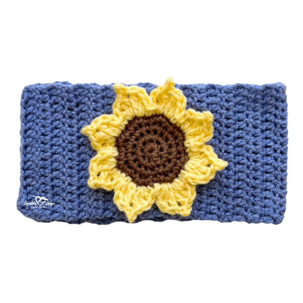 Handmade crochet headband with a large yellow sunflower applique sewn on a blue band. Free sunflower crochet headband pattern by Lovable Loops.