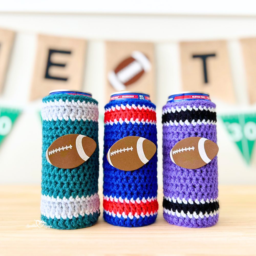 Three crochet slim can cozies in team colors (teal and gray, red and blue, purple and black) displayed in front of a football game day banner. Beginner-friendly crochet can cozy pattern for tailgates and sports fans.