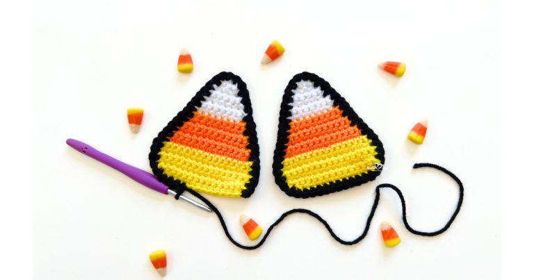 Two crochet candy corn appliques with black borders, worked in white, orange, and yellow yarn, displayed with candy corn pieces and a purple crochet hook.