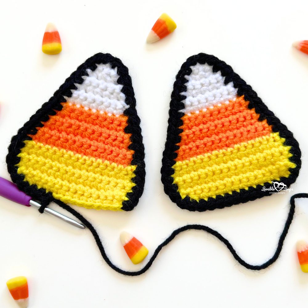 Two crochet candy corn appliques with black borders, displayed with candy corn pieces and a purple crochet hook, perfect for Halloween crafts and decorations.