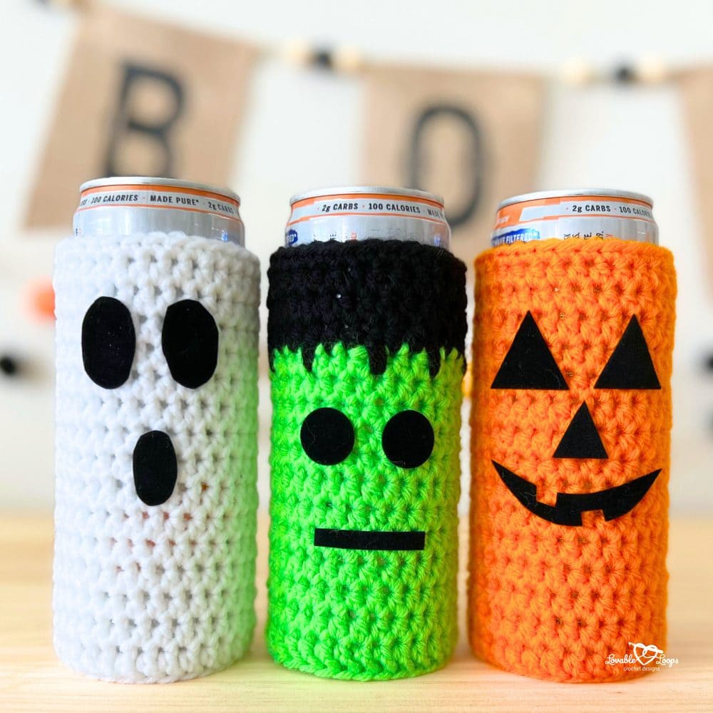 Finished Halloween crochet koozies on slim cans featuring a white ghost, green Frankenstein, and orange pumpkin. Fun, quick, and beginner-friendly crochet can cozy pattern.