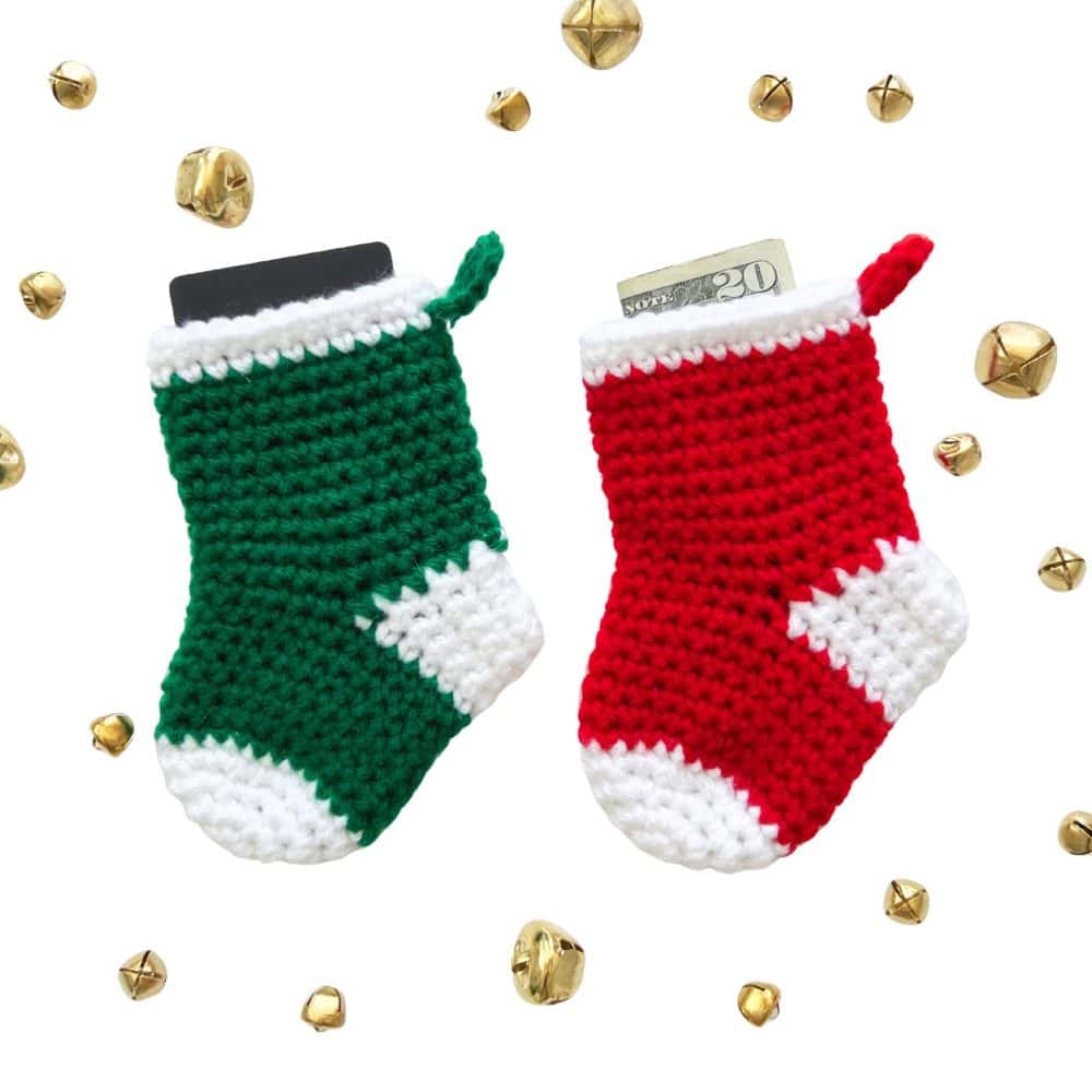 Two crochet mini stockings in red and green with white accents, shown filled with a gift card and cash. A festive Christmas crochet idea for ornaments or gift holders.