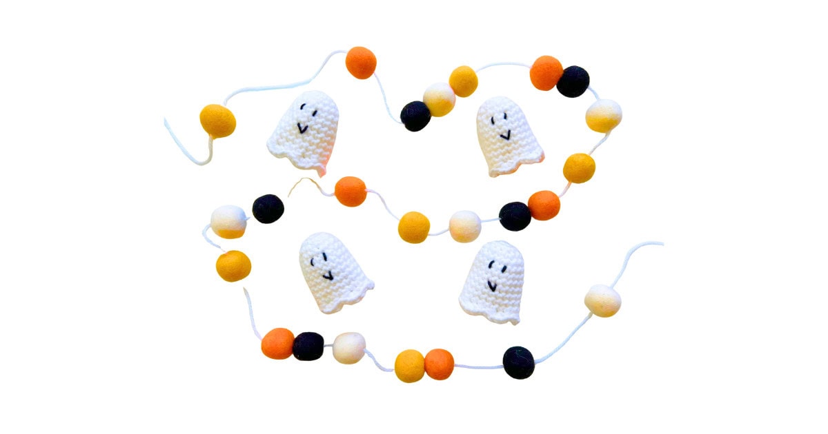 Handmade crochet ghost garland with white mini ghosts attached to a festive Halloween pom pom string in orange, black, and yellow.