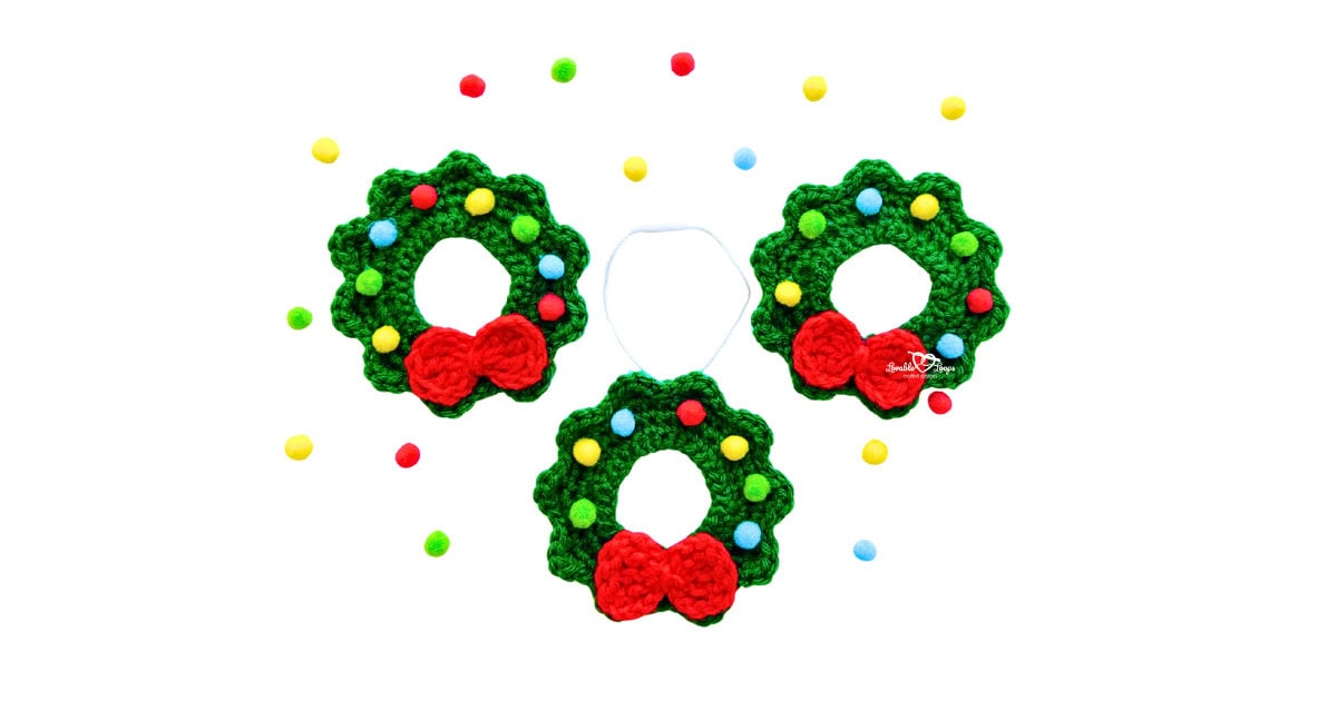 Three small crochet wreath ornaments with red bows and colorful pom poms, made using an easy crochet Christmas wreath pattern.