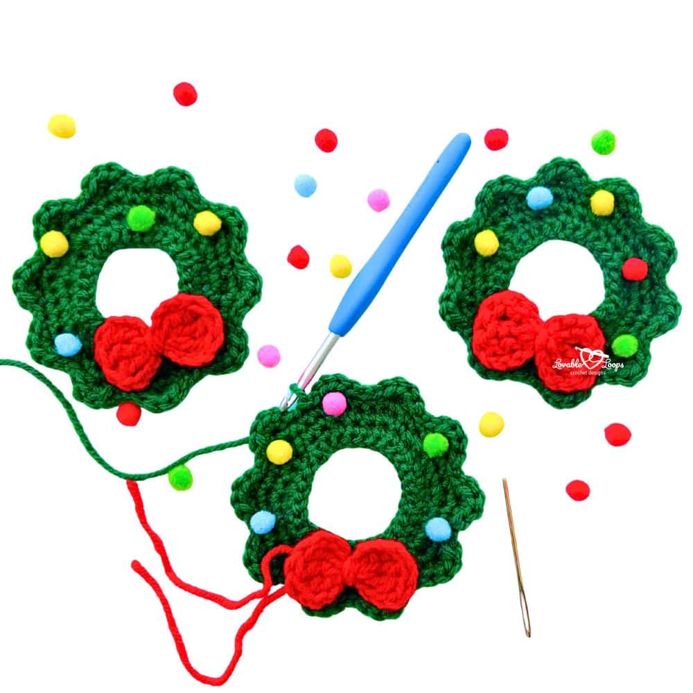 In-progress crochet wreath ornaments with red yarn, pom poms, and a crochet hook, showing how to make a mini crochet wreath ornament.