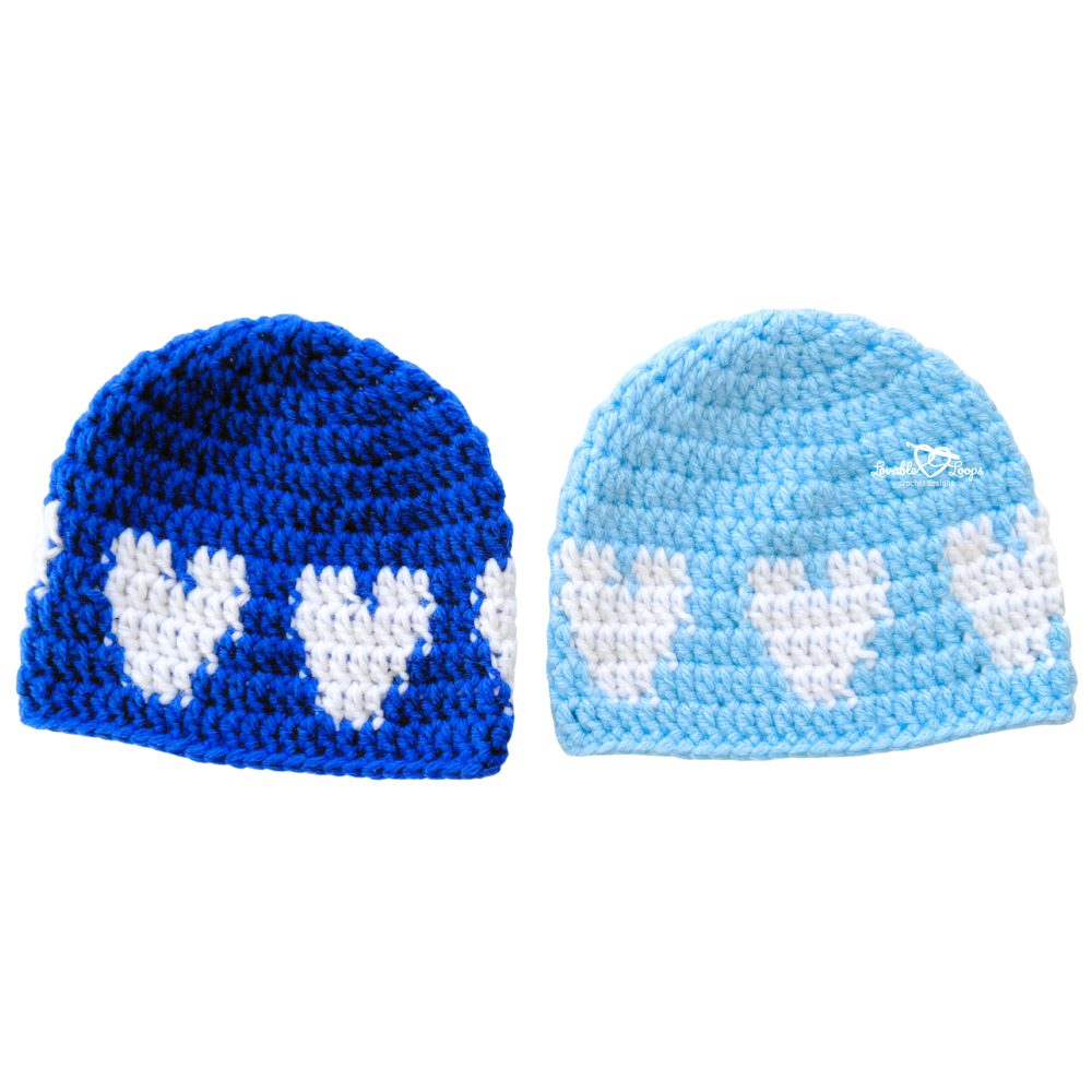 Two crochet baby hats side by side—royal blue and light blue—with repeating white hearts circling the hat. Soft, stretchy crochet heart hat pattern worked top down; easy baby hat crochet pattern.