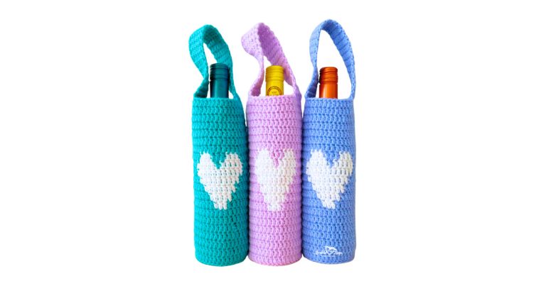 Three crochet wine bottle holders with straps in teal, pink, and blue, each with a white heart on the front&mdash;easy crochet wine bottle holder free pattern and reusable crochet wine bag gift.