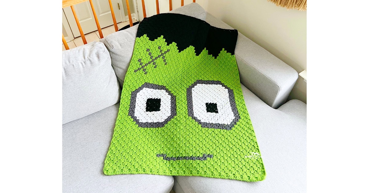 C2C Frankenstein blanket crochet pattern shown on a couch, featuring a green Frankenstein face with bold corner-to-corner colorwork, perfect for a kids Halloween blanket.
