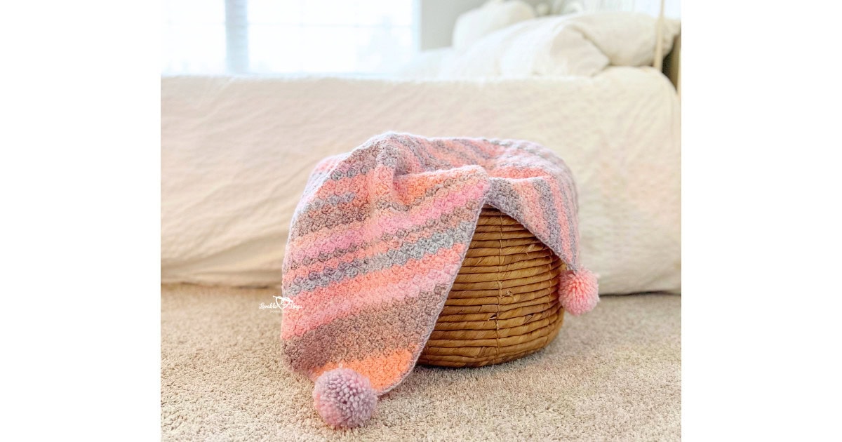 Finished C2C baby blanket crochet pattern displayed over a basket in a neutral bedroom setting, ideal for beginners