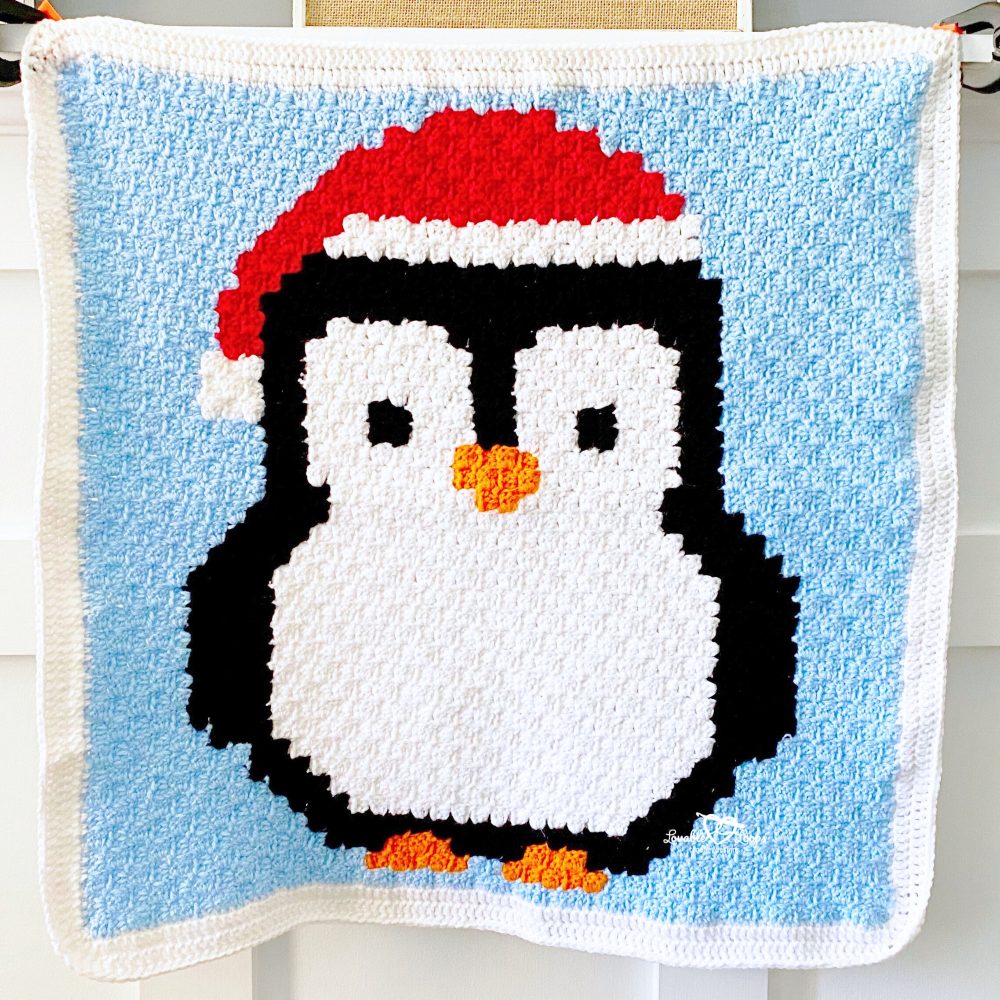 Close-up of the C2C penguin blanket crochet pattern showing textured stitches, bold colorwork, and winter penguin design