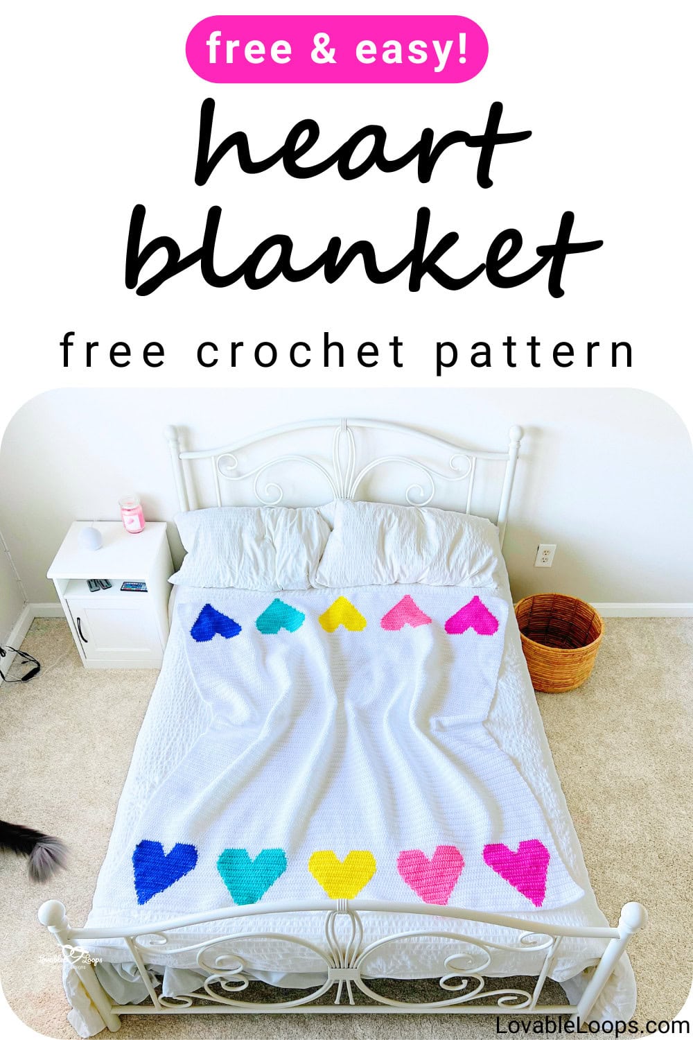 Free heart blanket crochet pattern featuring a white crochet blanket with colorful tapestry crochet hearts at the top and bottom, displayed on a bed.