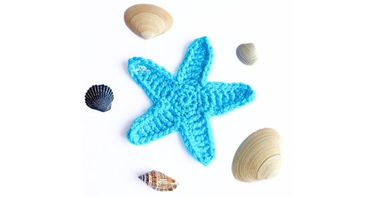 Blue crochet starfish applique made with worsted weight yarn, displayed on a white background with seashells, showcasing a free beginner-friendly starfish crochet pattern.