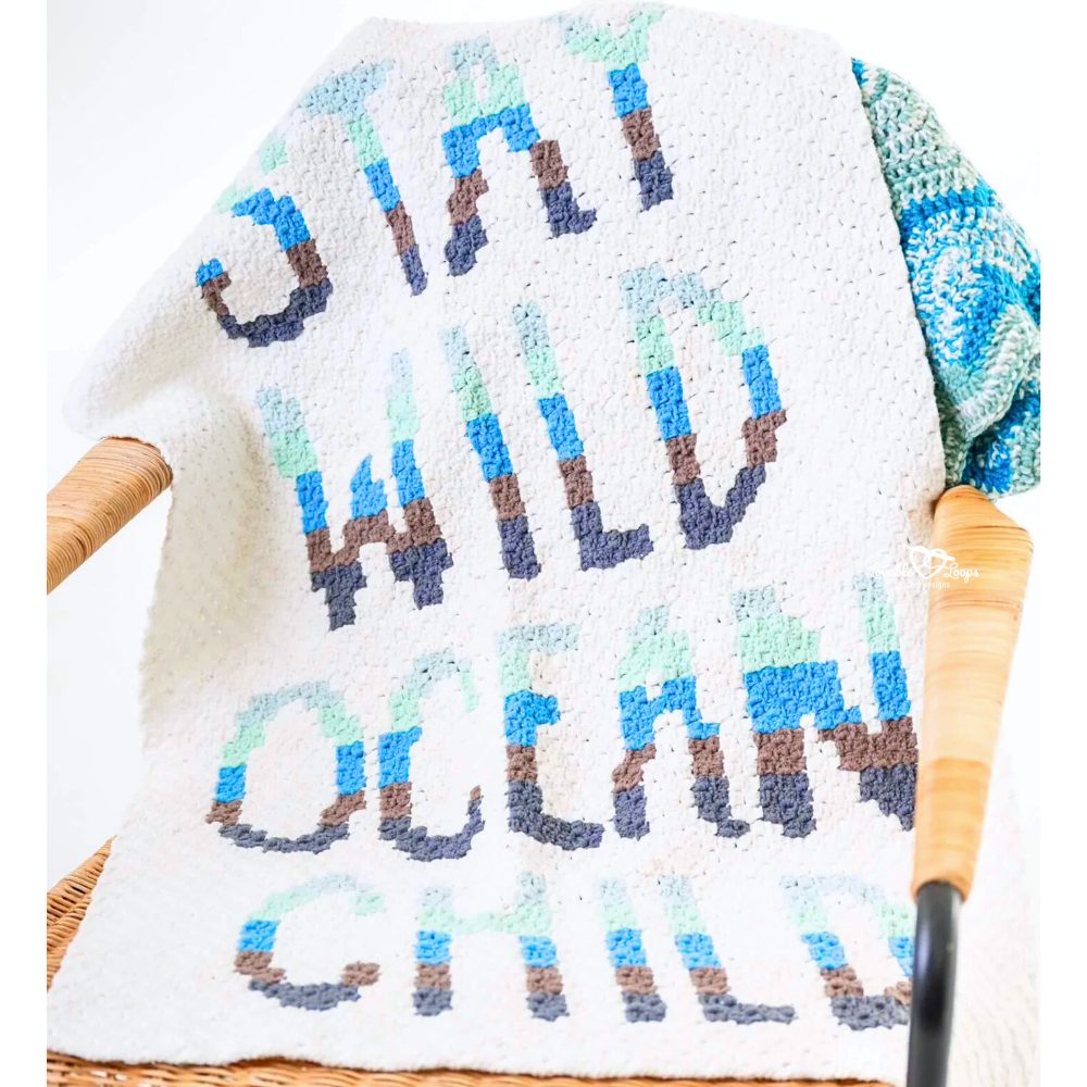 Close-up of a C2C crochet word blanket showing the phrase &ldquo;stay wild ocean child&rdquo; worked in corner to corner crochet stitches