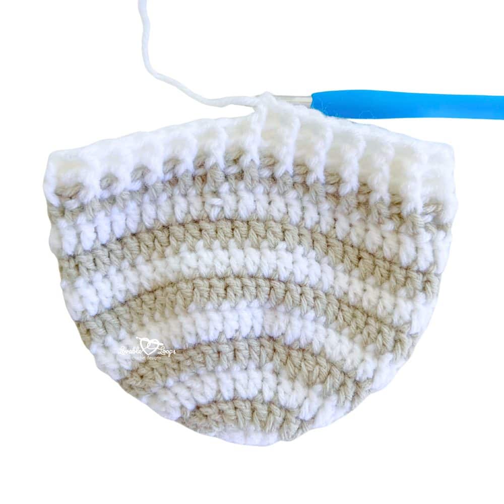 Top-down crochet beanie hat in progress, showing crown shaping and striped rounds worked in the round
