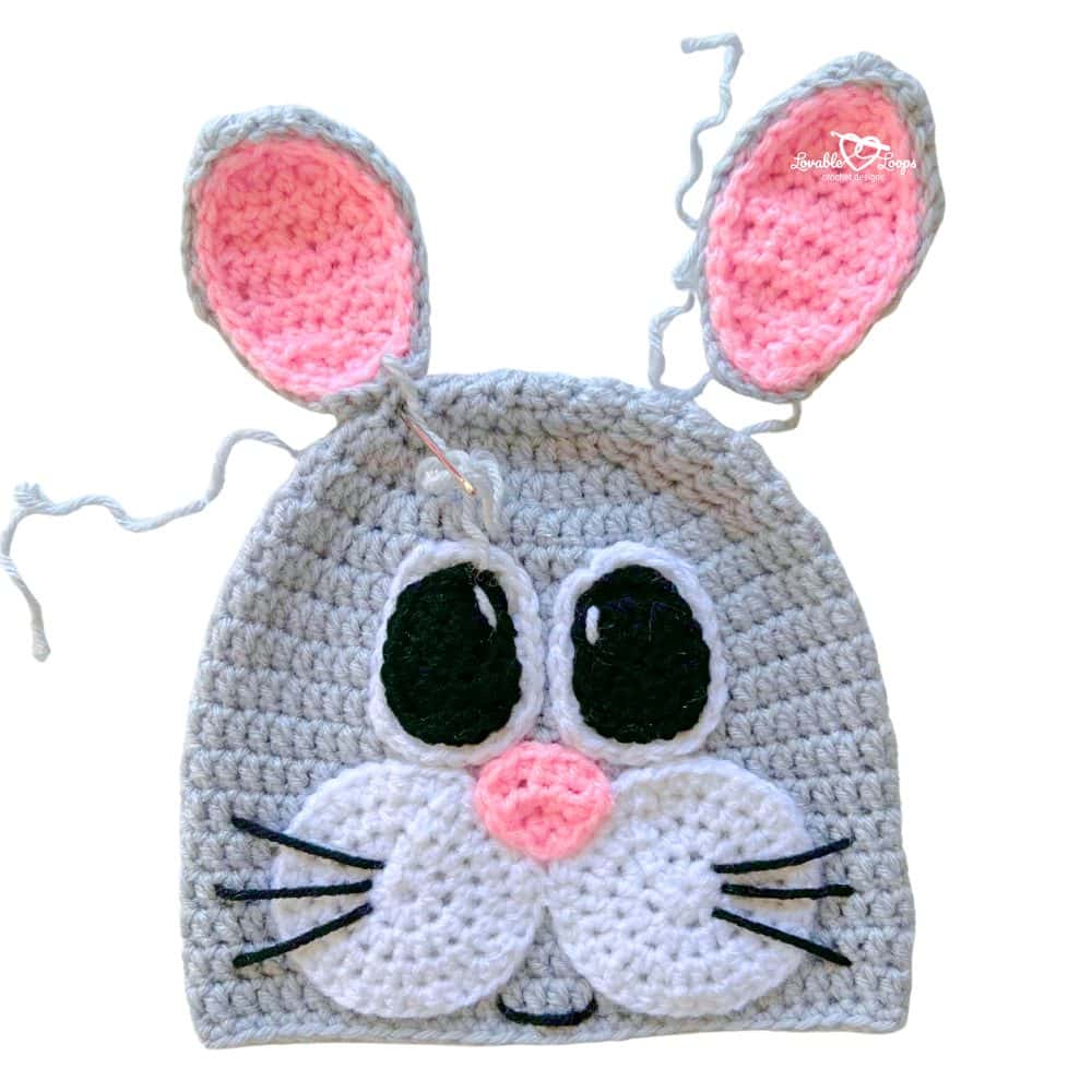 Crochet bunny hat pattern showing bunny ears positioned and pinned to the hat before sewing