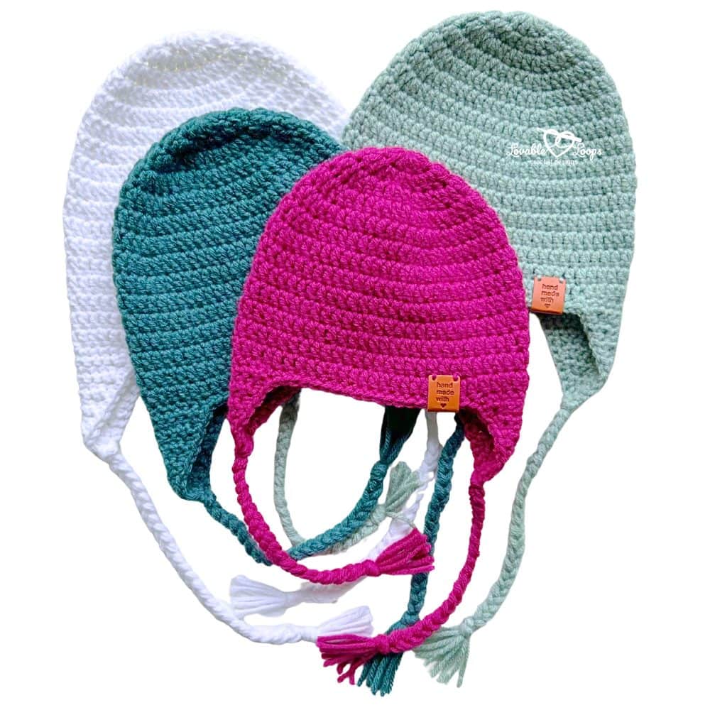 Crochet hats with ear flaps and braided ties shown in several colors, made using a free crochet ear flap hat pattern in all sizes