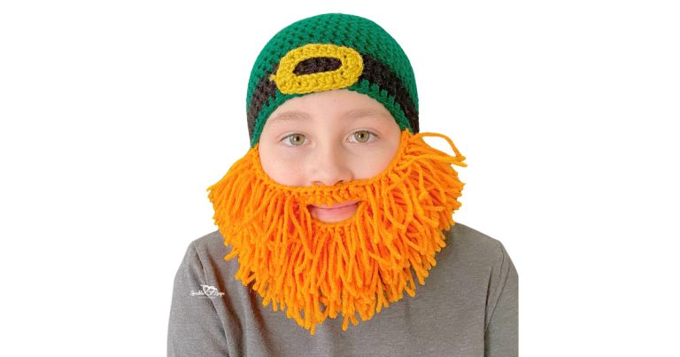 Child modeling a crochet leprechaun beard hat pattern featuring a green top-down beanie, black band with gold buckle, and bright orange yarn beard for St. Patrick’s Day.