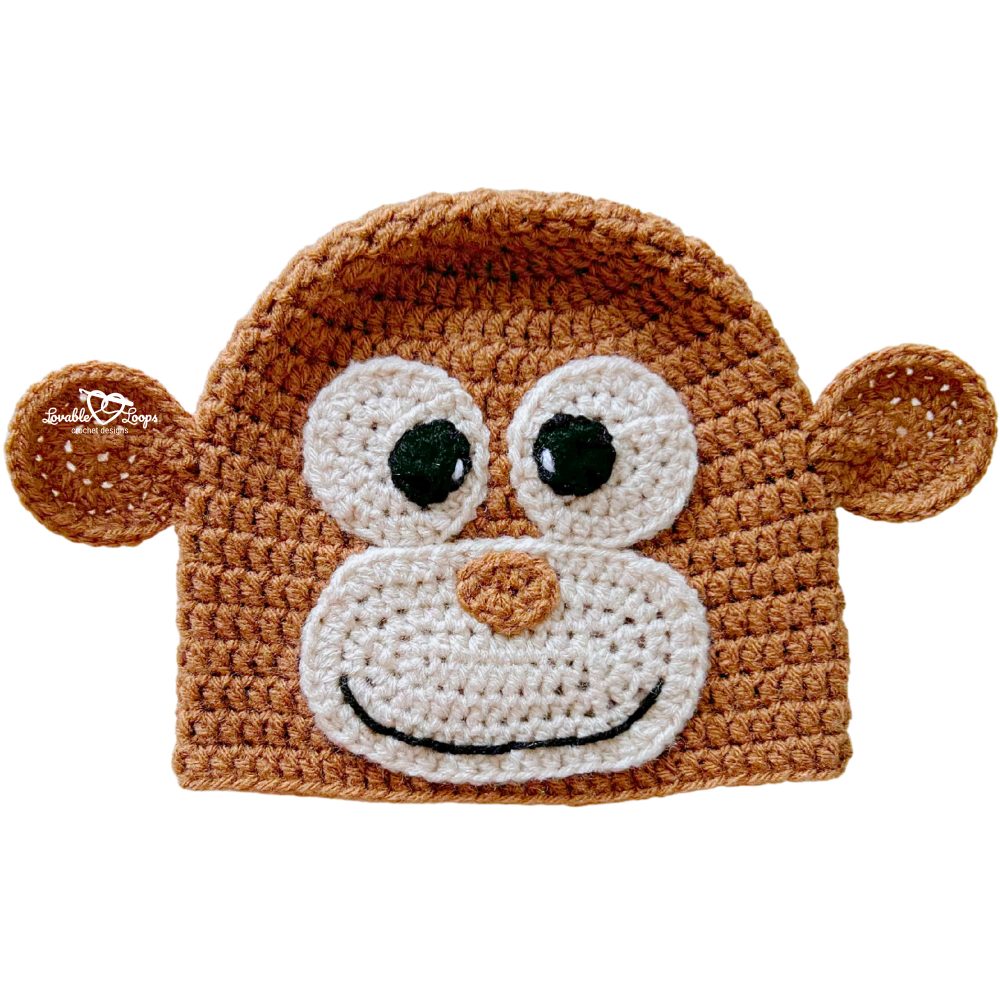 Handmade crochet monkey beanie in brown with floppy round ears, big eyes, and a smiling monkey face.