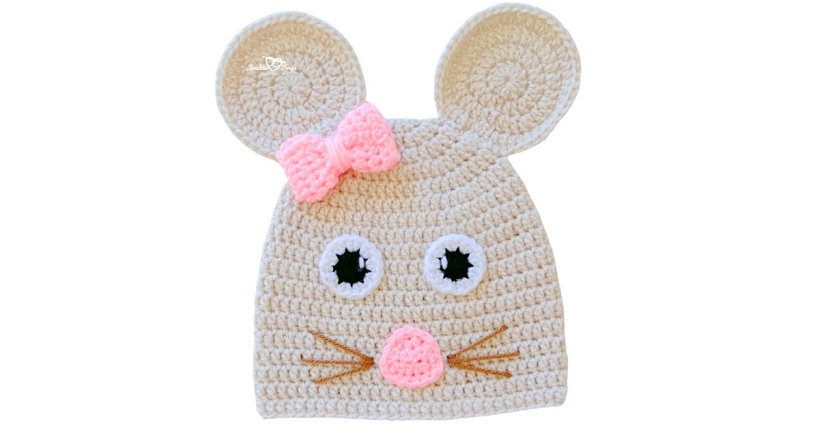 Light beige crochet mouse hat with oversized round ears, pink bow, pink nose, and embroidered whiskers.