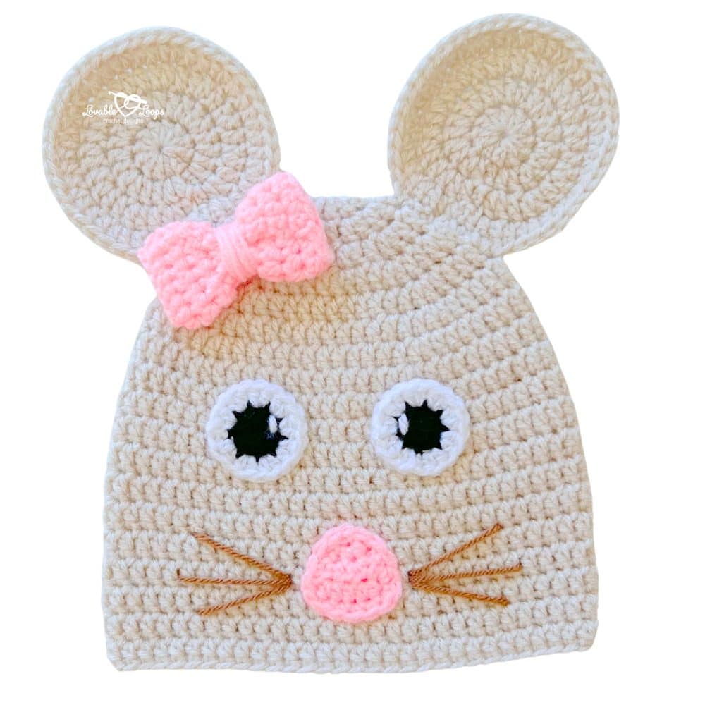Handmade crochet mouse beanie in cream with large ears, a pink bow, pink nose, and whisker details.