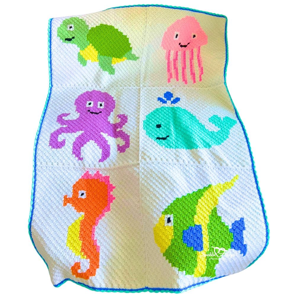Corner-to-corner C2C crochet sea animals blanket featuring six bright ocean creatures including a turtle, jellyfish, octopus, whale, seahorse, and tropical fish on a white background with blue edging.