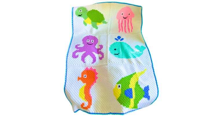 Full view of a C2C crochet ocean animals blanket with colorful sea creatures arranged in panels, worked in diagonal corner-to-corner stitches with a blue border.