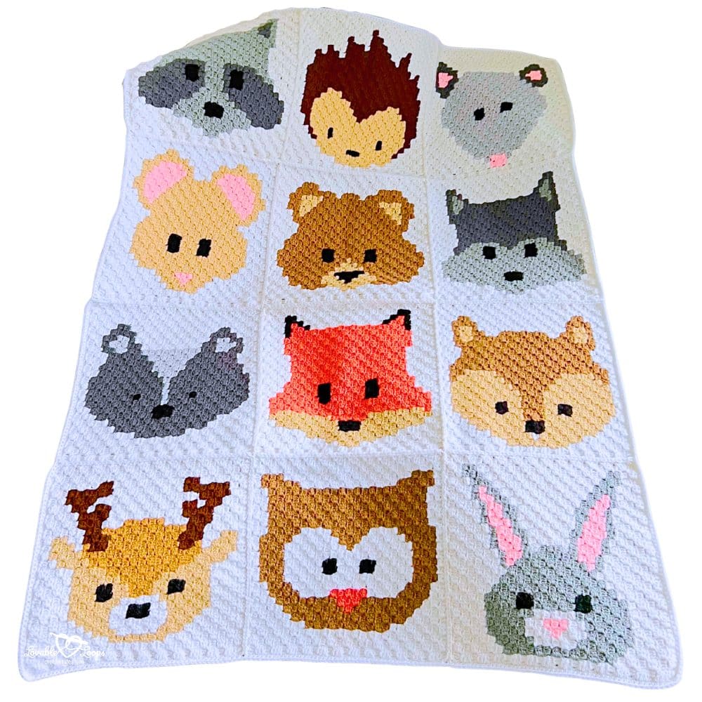 Woodland animal C2C baby blanket made from 12 corner to corner crochet squares sewn together, showing fox, bear, owl, bunny, deer, and forest nursery theme designs.