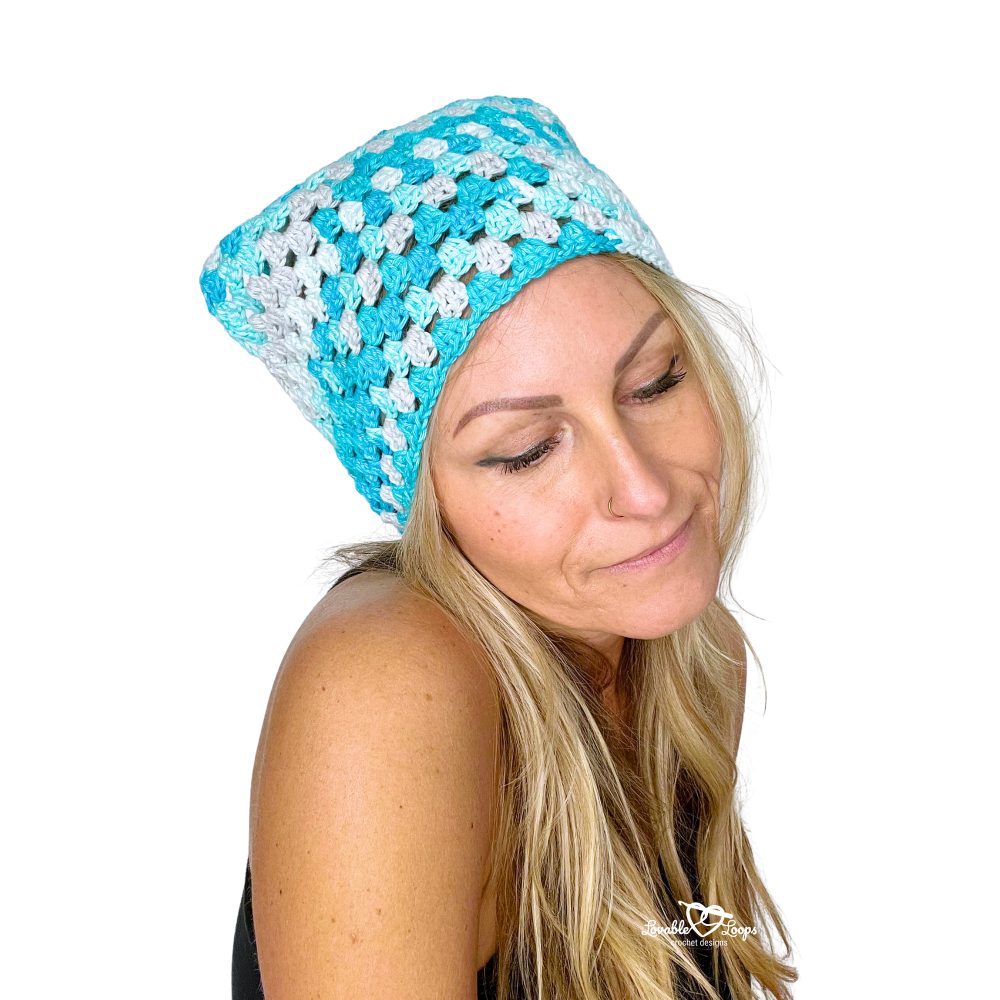Model wearing a blue crochet bandana made with the classic granny stitch in a lightweight triangular design