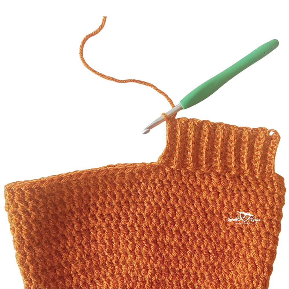 Close-up of a men&rsquo;s crochet hat pattern in burnt orange yarn showing the ribbed brim being worked with an I-9 (5.5 mm) crochet hook.