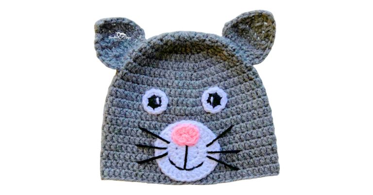 Gray crochet cat hat with pointed ears, white muzzle, pink nose, stitched smile, and black whiskers.
