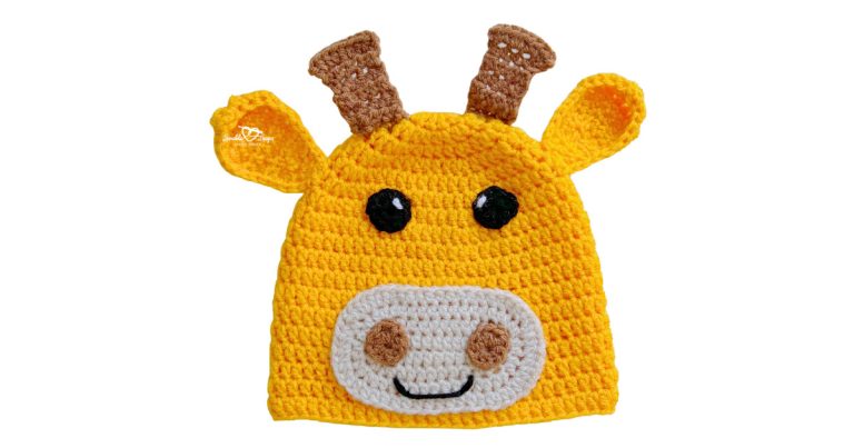 Yellow crochet giraffe hat with brown horns, ears, black eyes, and a white muzzle with a stitched smile.