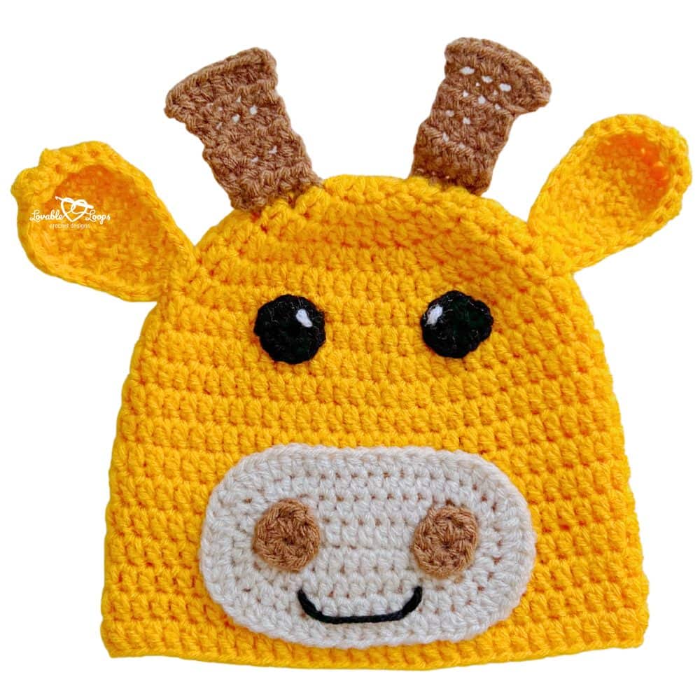Bright yellow crochet giraffe beanie with little brown horns, floppy ears, and a smiling giraffe face.