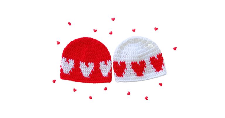 Two baby beanies made from a crochet heart hat pattern: one red hat with white hearts and one white hat with red hearts; beginner-friendly crochet baby hat pattern sized 6–12 months.