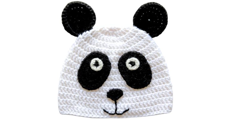 White crochet panda hat with black ears, black eye patches, and a stitched nose and smile, shown on a light background.