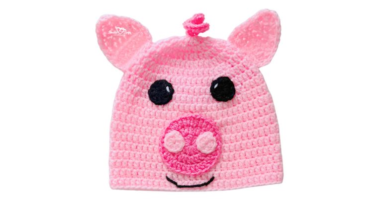 Pink crochet pig hat with pointed ears, curly top detail, black eyes, and a round pink snout applique.