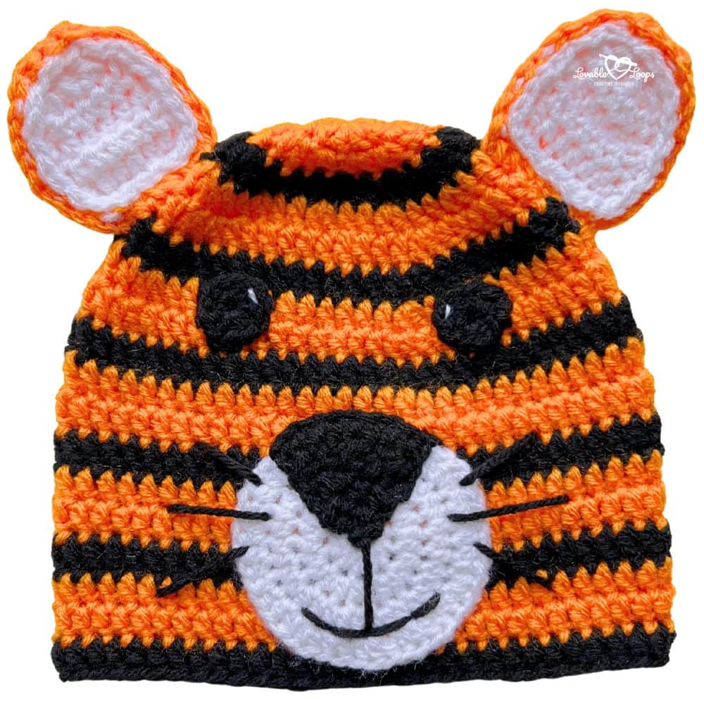 Orange and black striped crochet tiger hat with ears, black nose, white muzzle, and embroidered whiskers.